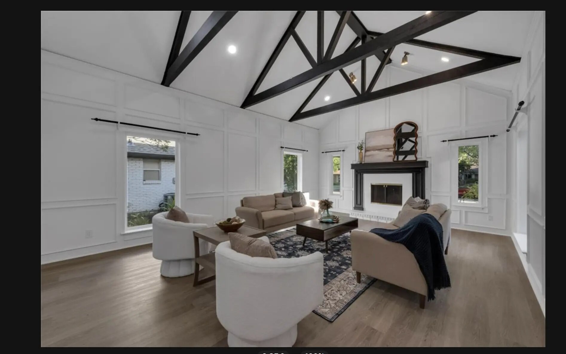 Staged living room with vaulted ceiling, black beams, and a fireplace