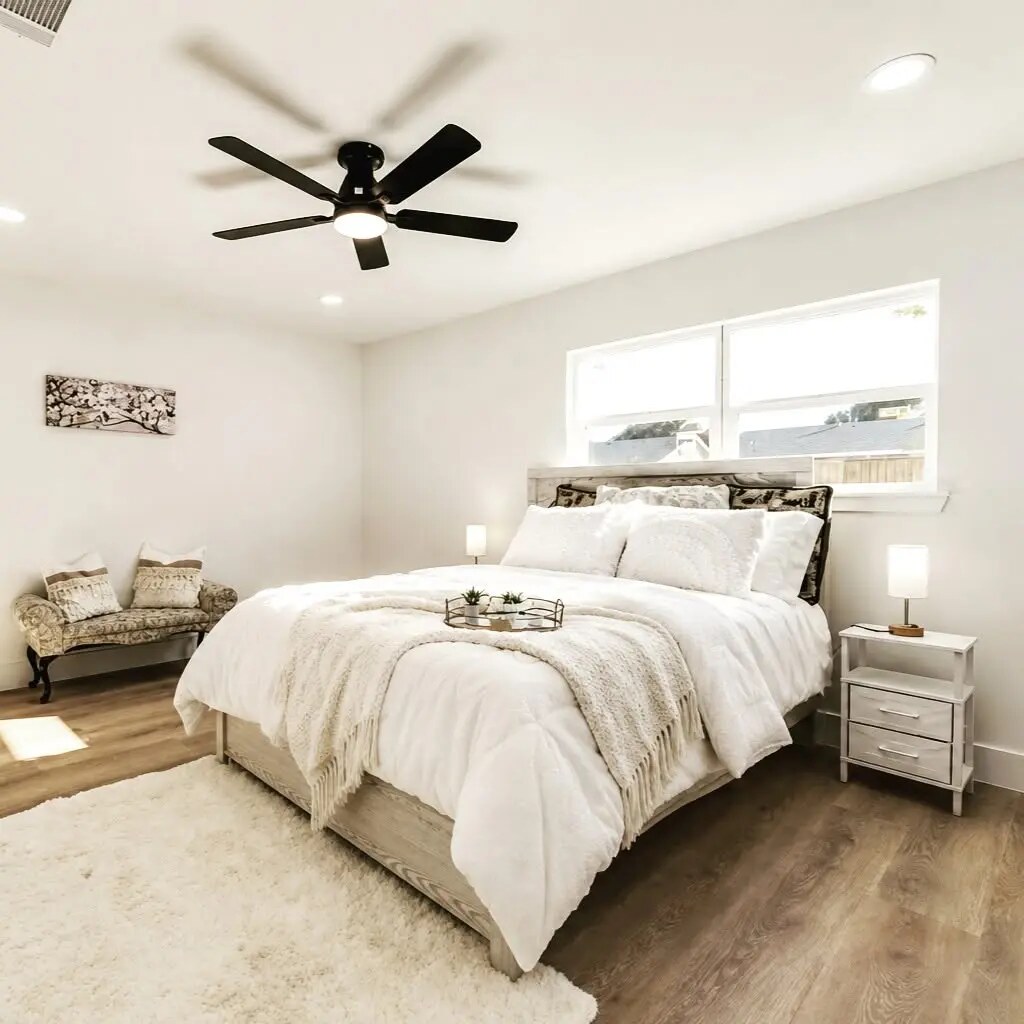 Neutral primary bedroom staged with layered white bedding
