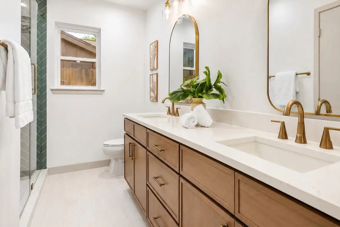 Double-vanity bathroom styled with warm brass fixtures and greenery